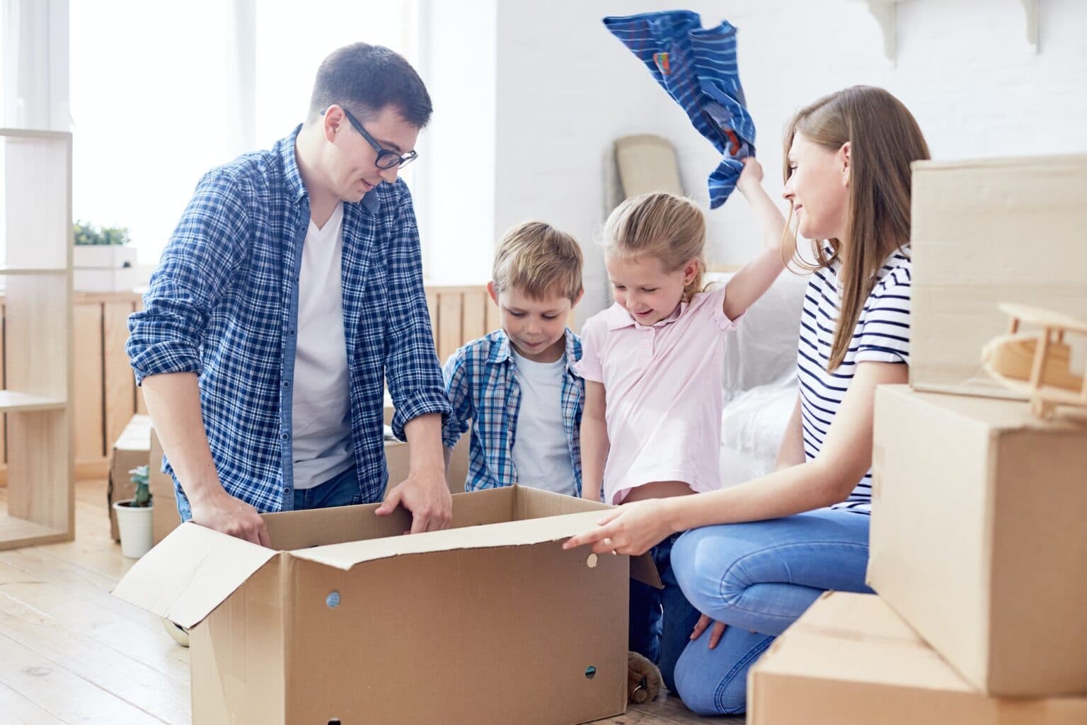 Family packing moving boxes with children